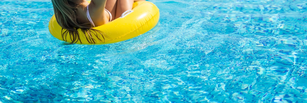 Frau mit gelbem Schwimmring im Outdoor-Pool