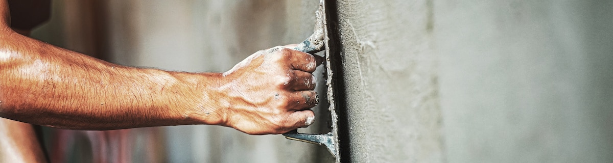 Nahaufnahme der Hand eines Arbeiters, der eine Wand verputzt