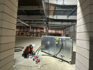 Winterbauheizung für Neubauprojekt: Heizungstechniker von Mobile Wärme 24 bei der Installation einer Warmluftturbine