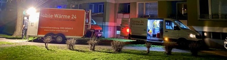 Ein Heizmobile und ein Transporter von Mobile Wärme 24 nachts vor einem Wohngebäude